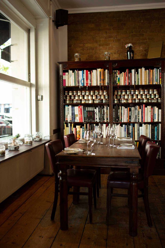 Kitchen-Library brauner, gedeckter Restaurant-Holztisch vor Bücherregal